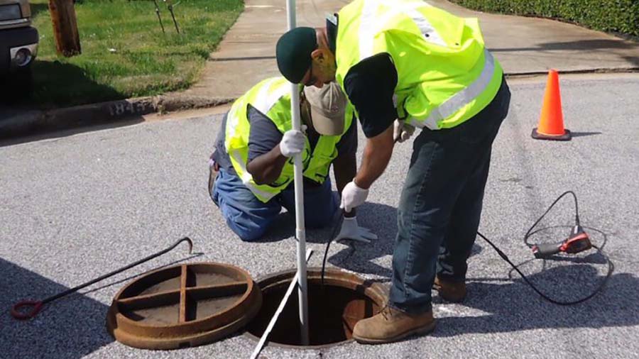 Two water utility contractors performing a manhole inspection - how engineers leverage environmental compliance technology